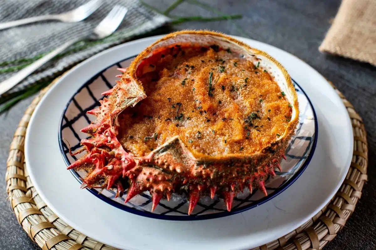 Txangurro a la donostiarra, un delicioso relleno de marisco gratinado en su propio caparaz&oacute;n, adornado con perejil picado.