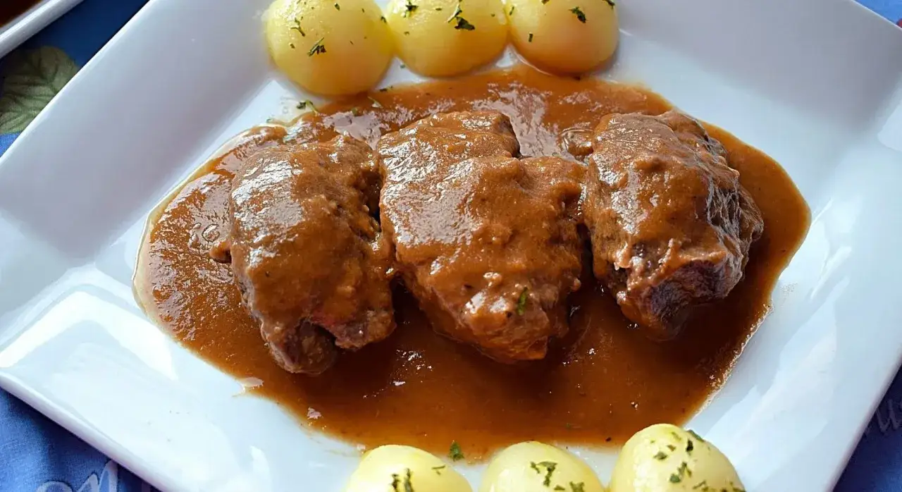 Carrilleras de ternera estofadas en salsa, acompañadas de patatas cocidas y espolvoreadas con perejil. Un plato casero y delicioso.