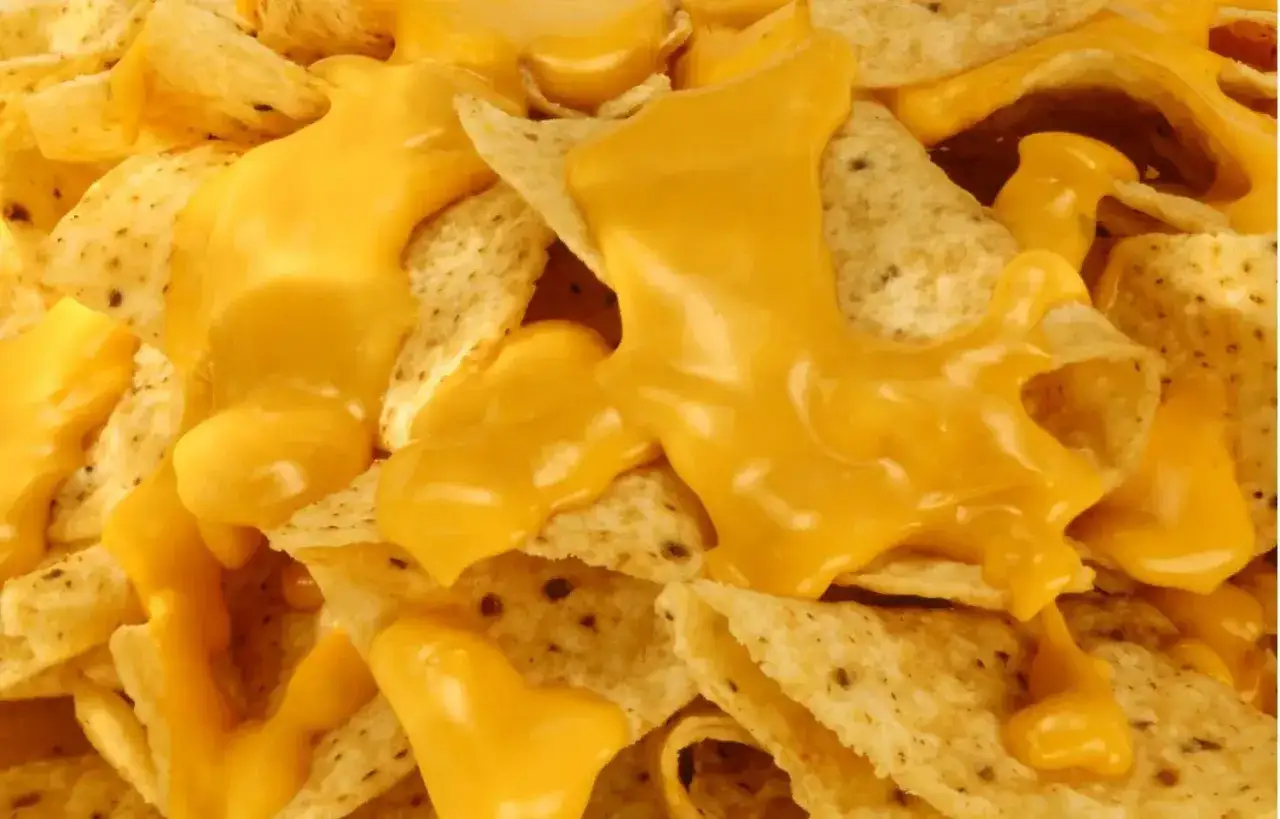 Nachos con queso derretido, una deliciosa combinación de crujientes totopos cubiertos con queso amarillo fundido.