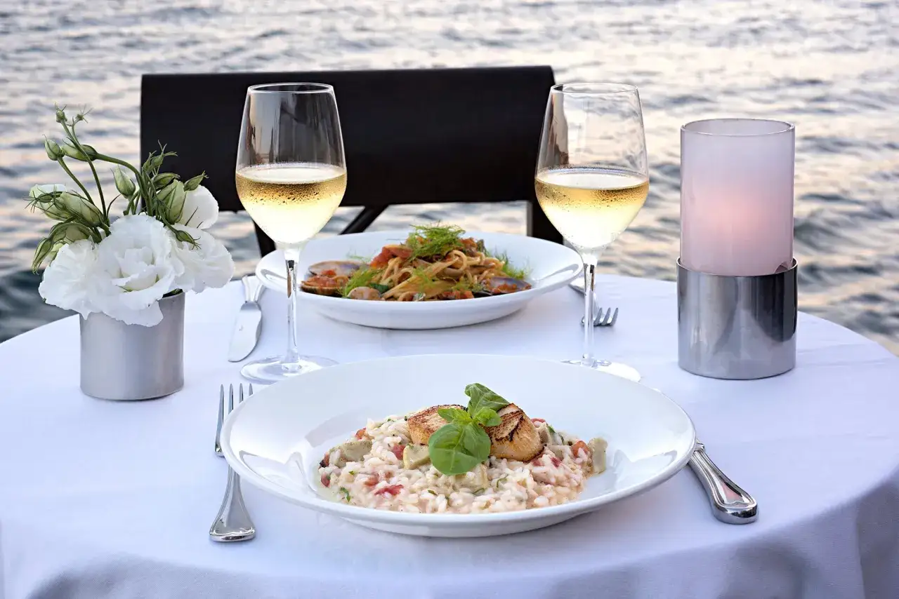 Cena rom&aacute;ntica junto al mar con dos copas de vino blanco, risotto de vieiras y pasta con mariscos. Perfectos tipos de vino blanco para la ocasi&oacute;n.