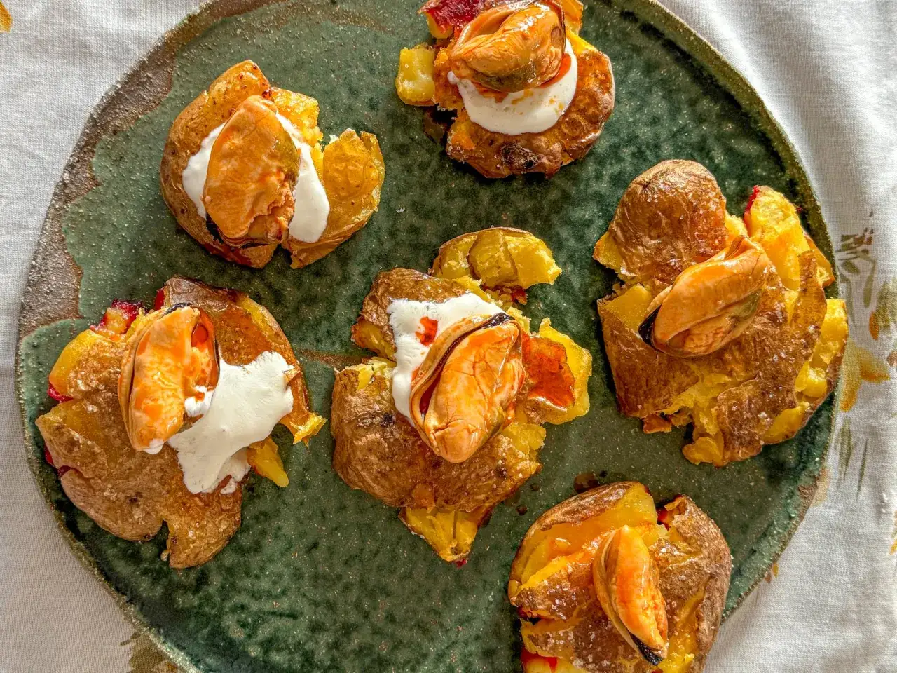 Patatas aplastadas con mejillones y crema. Un delicioso aperitivo que combina la textura crujiente de la patata con el sabor del mar.