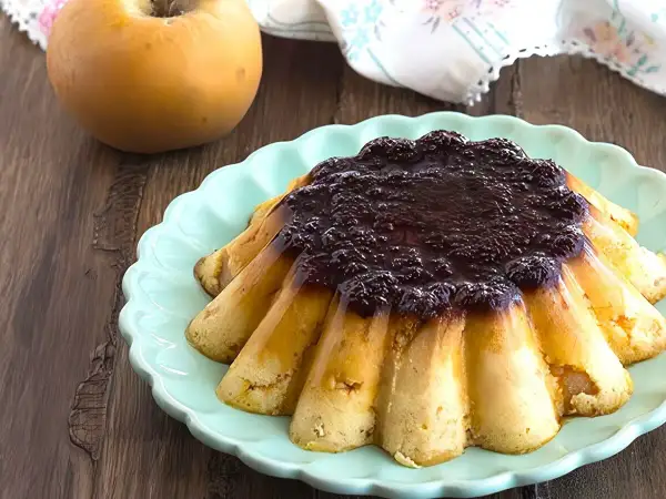 Delicioso pudin de manzana con cobertura oscura, servido en plato turquesa.