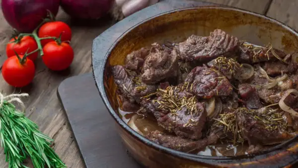 Carrilleras de ternera estofadas con romero y cebolla, servidas en cazuela de barro.