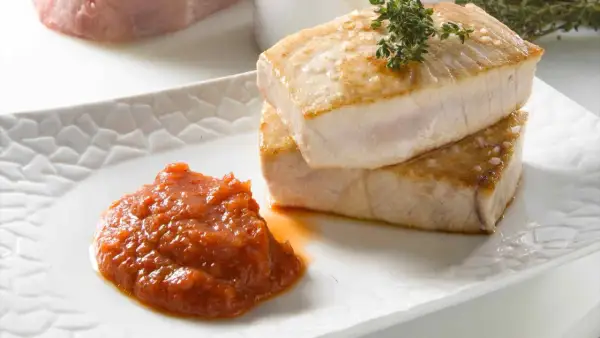 Dos jugosos medallones de atún a la plancha, con sal marina y romero, acompañados de una salsa de tomate casera.