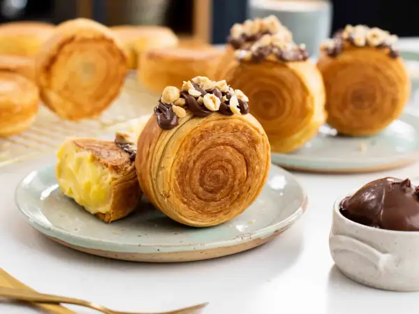 Deliciosos new york rolls cubiertos de chocolate y avellanas, uno abierto revela un cremoso relleno.