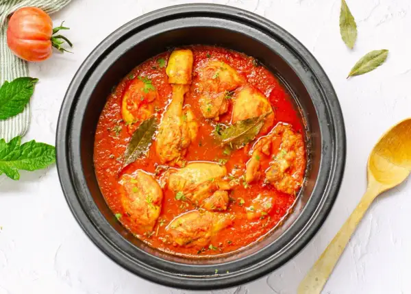 Sabroso pollo con tomate cocinado a fuego lento, con hojas de laurel y perejil picado.