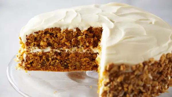 Delicioso pastel de zanahoria con glaseado cremoso y nueces picadas en los bordes.