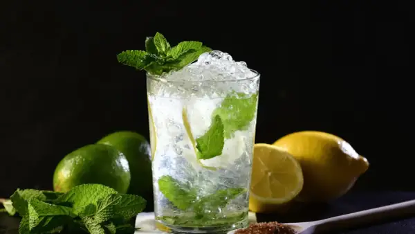 Un refrescante mojito con hielo picado, menta y rodajas de limón. Ingredientes para una mojito receta perfecta.