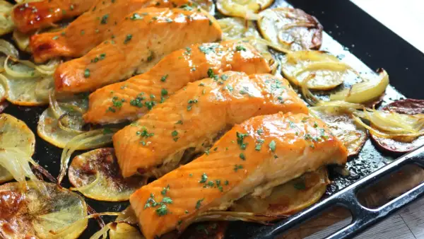 Filetes de salmón al horno, dorados y jugosos, servidos sobre patatas y cebolla asadas. Un plato delicioso y saludable.