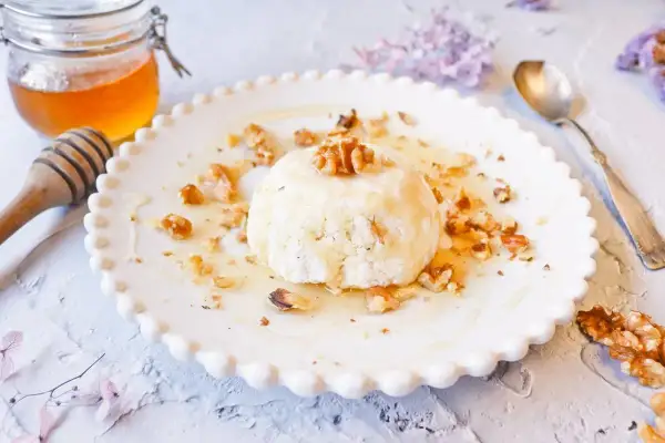 Delicioso mel y mató con nueces, servido en un plato blanco con borde festoneado.