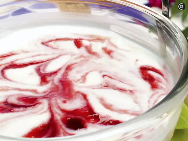 Delicioso helado de queso con remolinos de fresa en un tazón de vidrio.
