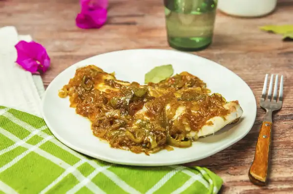 Delicioso plato de urta a la roteña, con pescado blanco cubierto de cebolla caramelizada y pimientos verdes.
