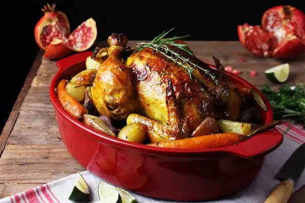 Pollo asado dorado con patatas y zanahorias, perfecto para tus recetas con pollo. Acompañado de granada y lima.