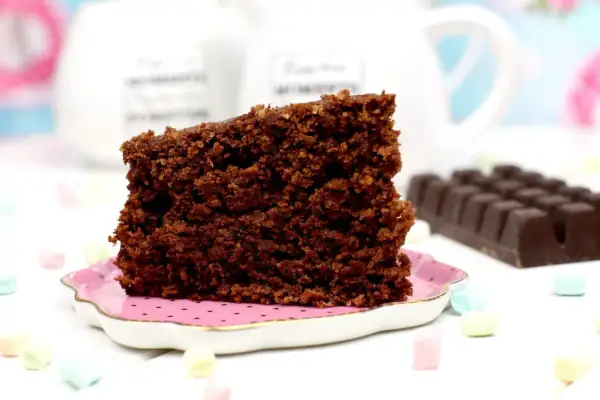 Un trozo de bizcocho de avena de chocolate, esponjoso y delicioso, servido en un plato rosa.
