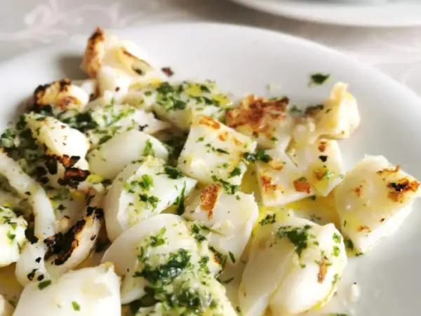 Sabrosa sepia a la plancha, cortada en trozos y aderezada con perejil fresco y aceite de oliva.