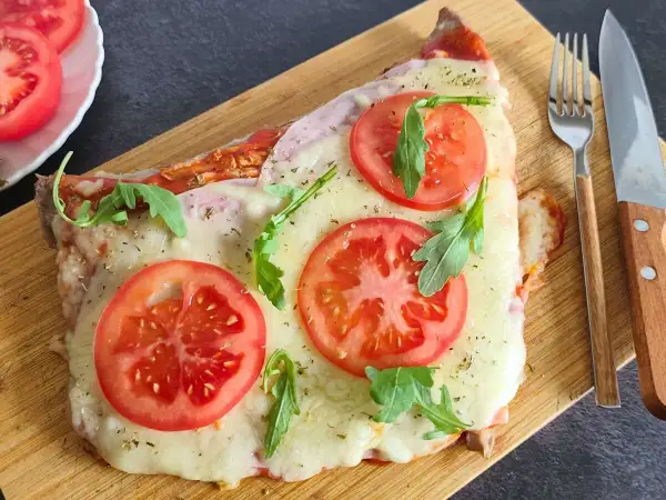 Un delicioso matambre a la pizza, cubierto de queso derretido, rodajas de tomate fresco y rúcula, servido en tabla de madera.