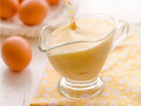 Crema pastelera lista para usar, con huevos frescos al fondo. ¡Perfecta para tu próxima receta!
