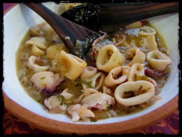 Calamares en salsa, un plato casero con trozos tiernos y tentáculos, servido en un cuenco de barro.