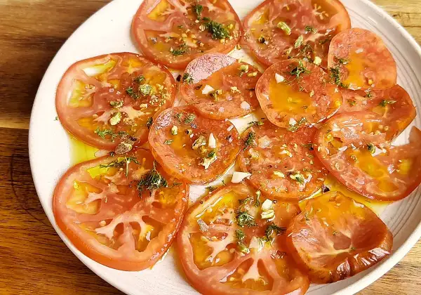 Delicioso carpaccio de tomate con aceite de oliva, ajo picado, hierbas frescas y trocitos de pistacho.